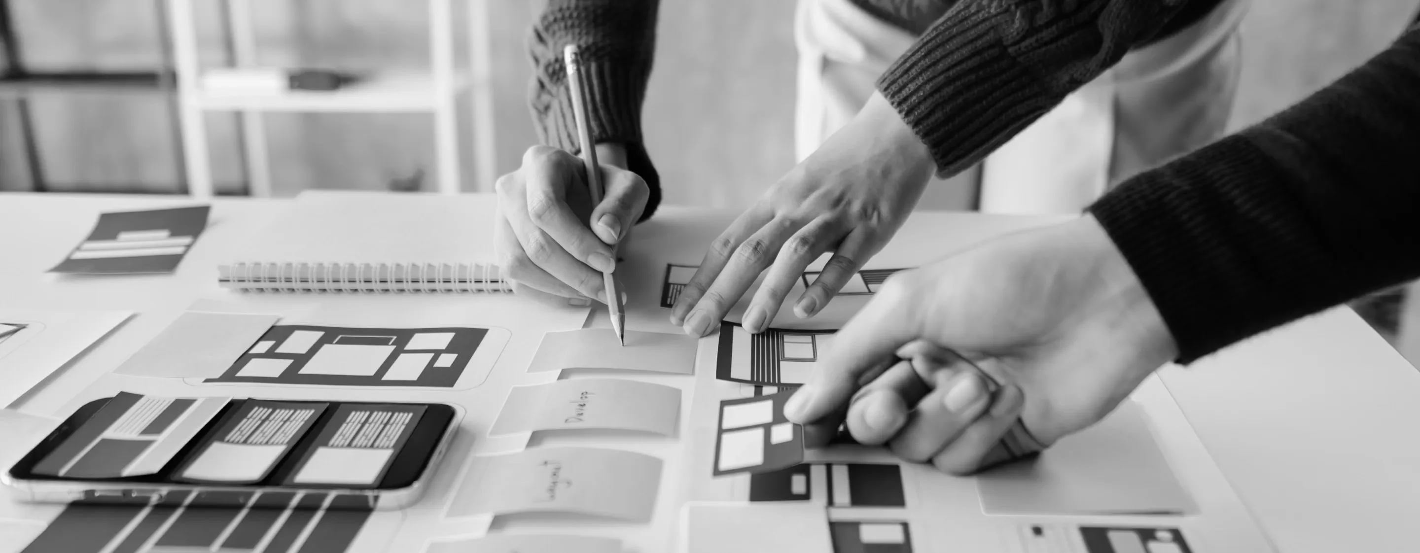 Foto delle mani di due persone che lavorano ad un tavolo studiando il percorso utente di un'app